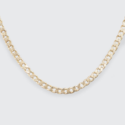 A flat curb chain in yellow gold