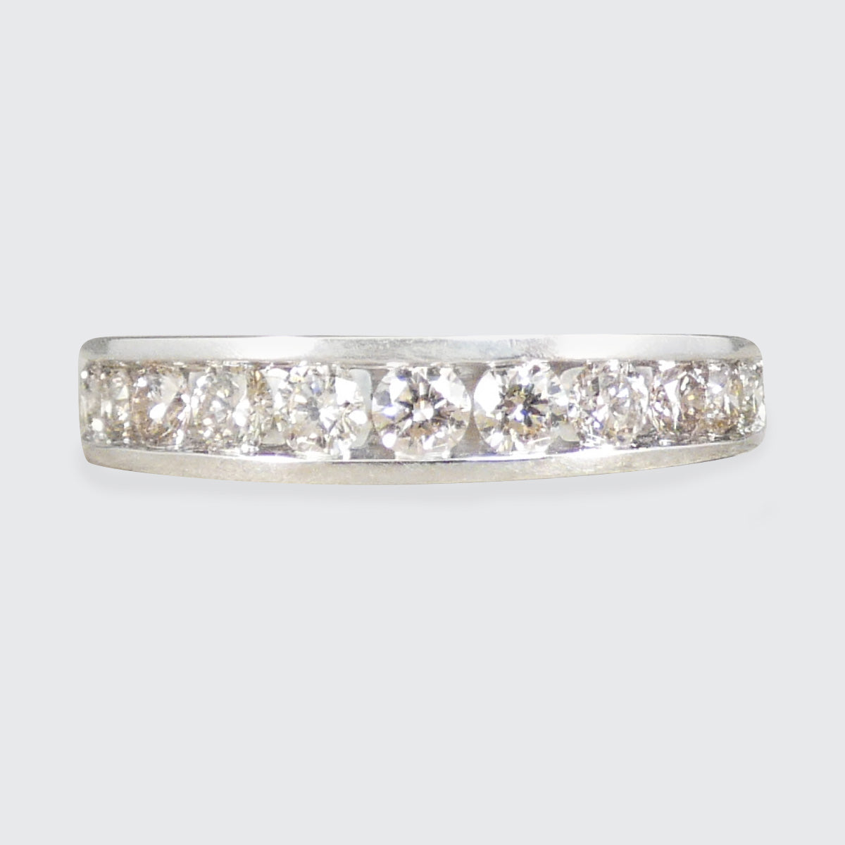 A white gold diamond eternity ring with five round-cut diamonds set in a polished silver band, shown against a light gray background.