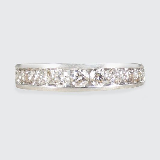 A white gold diamond eternity ring with five round-cut diamonds set in a polished silver band, shown against a light gray background.