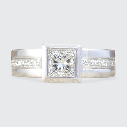 Platinum ring with a central diamond and smaller diamonds on the band against a light gray background