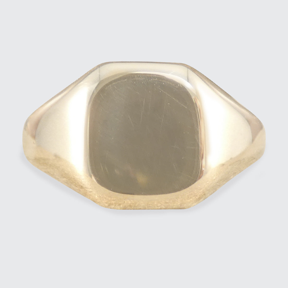 Gold signet ring on a light gray background