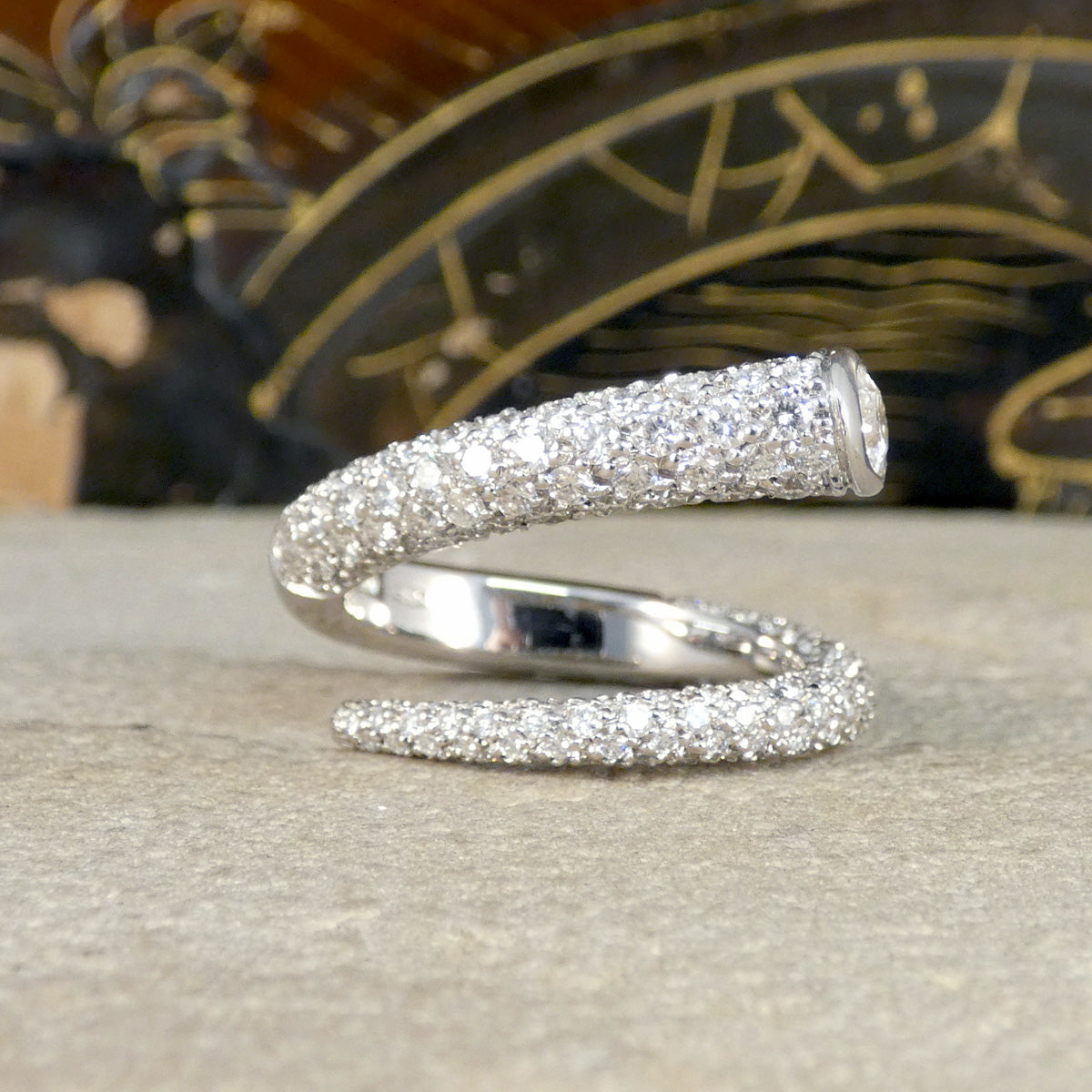A unique diamond set snake like ring shown on a stone.