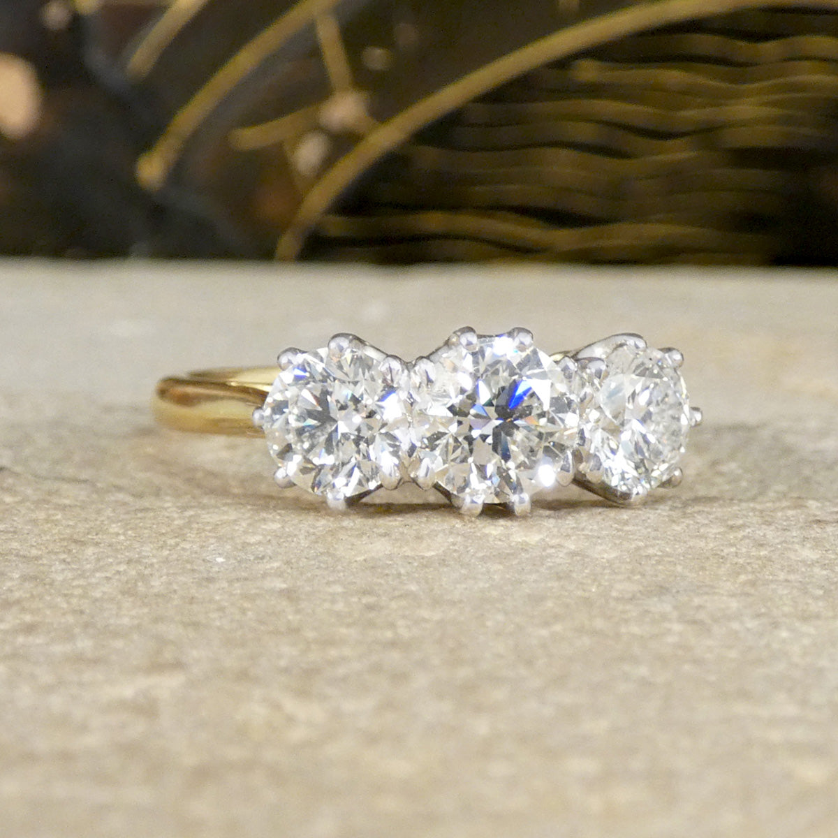 Gold ring with three diamonds on a textured surface