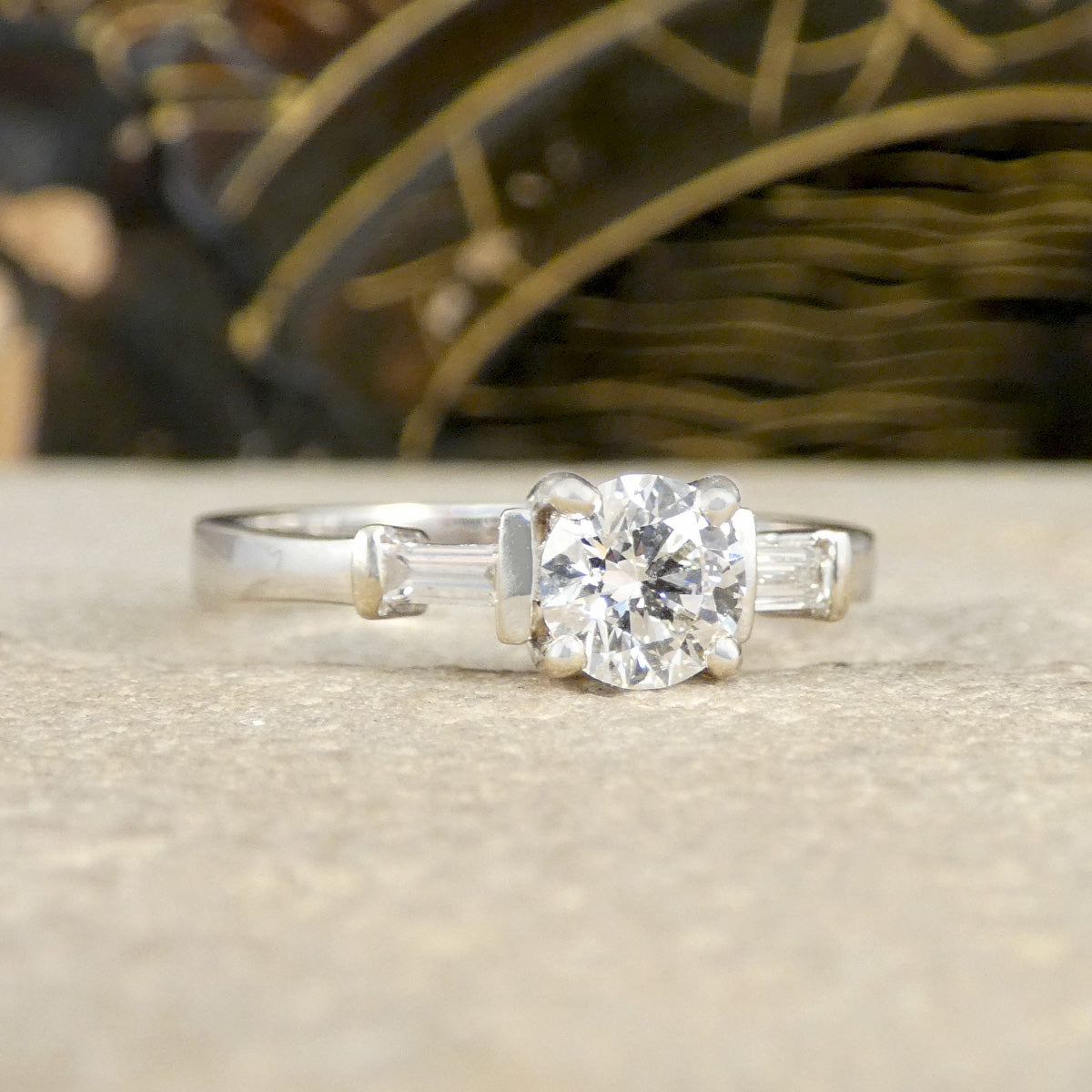 Diamond ring with baguette side stones on a neutral background