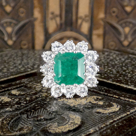 Front view of emerald and diamond cluster ring. Showing a bright and vibrant green hue.