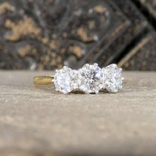 Three-stone diamond ring on a textured surface with a blurred background