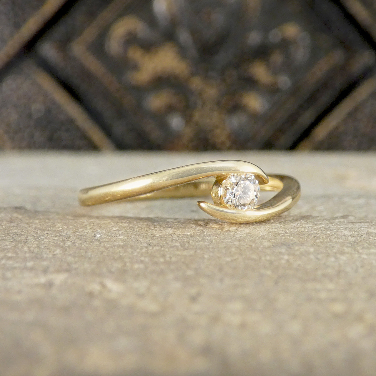 Gold ring with a diamond on a textured surface