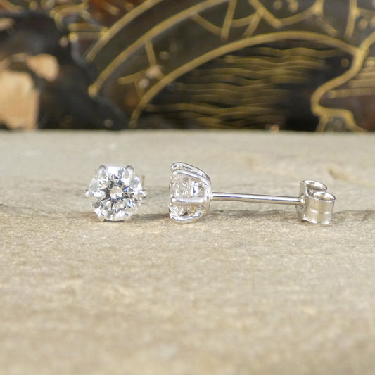 A pair of diamond stud earrings with six claws, one shown from the front and the other from the side.