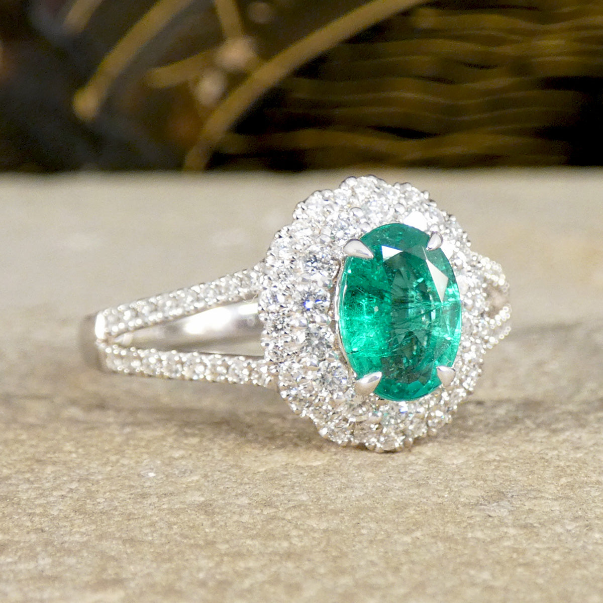 Ring with a green gemstone and diamond halo on a neutral background
