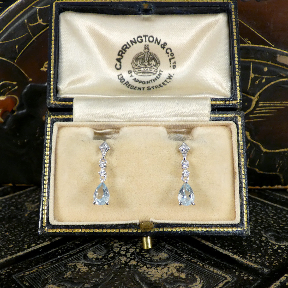 Pair of diamond and Aquamarine drop earrings in a jewellery box on a decorative background