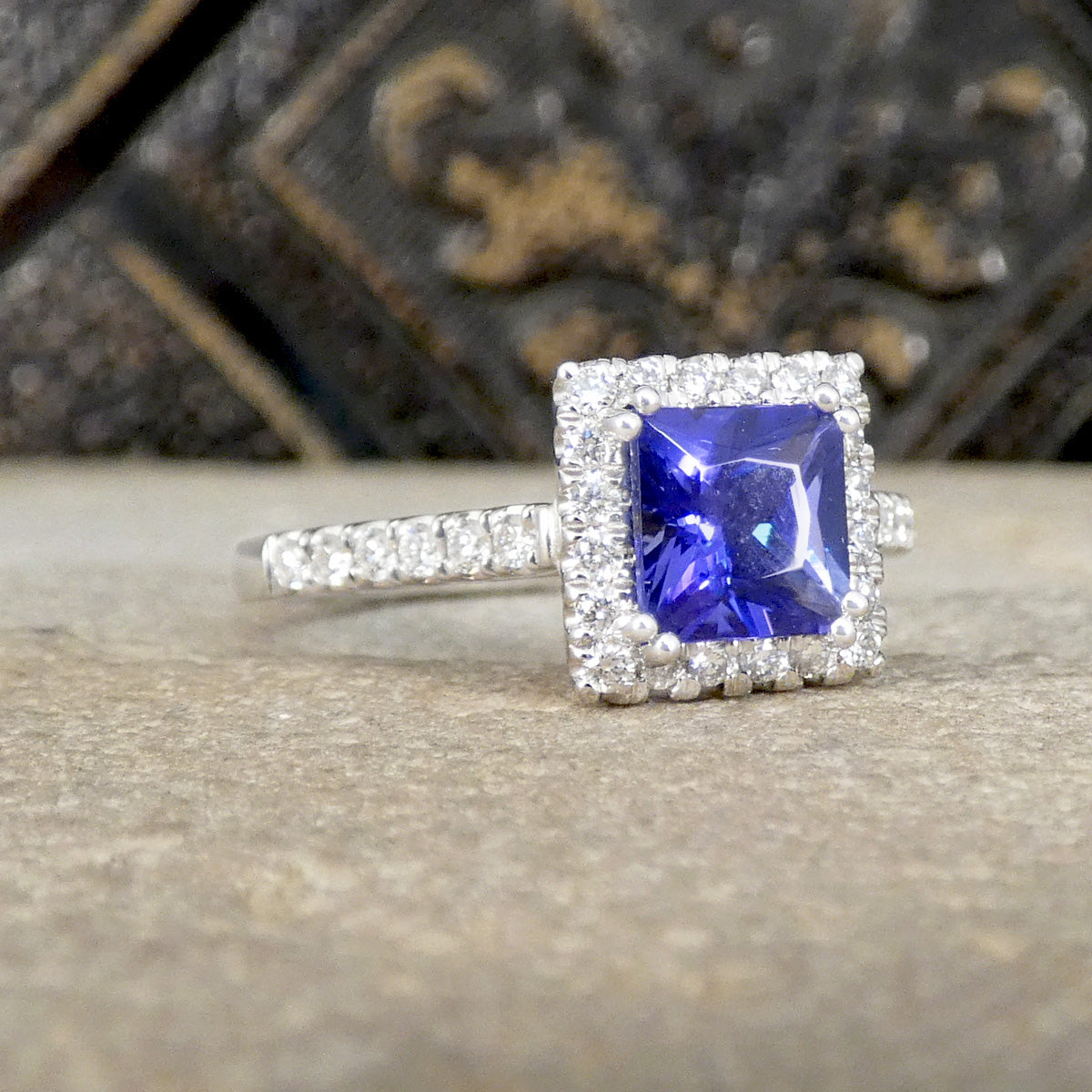 Ring with a blue gemstone and diamond accents on a textured surface