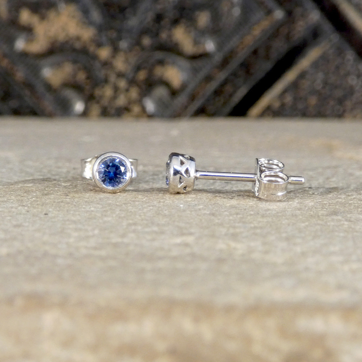 Silver ring and earrings with blue gemstone on a textured surface