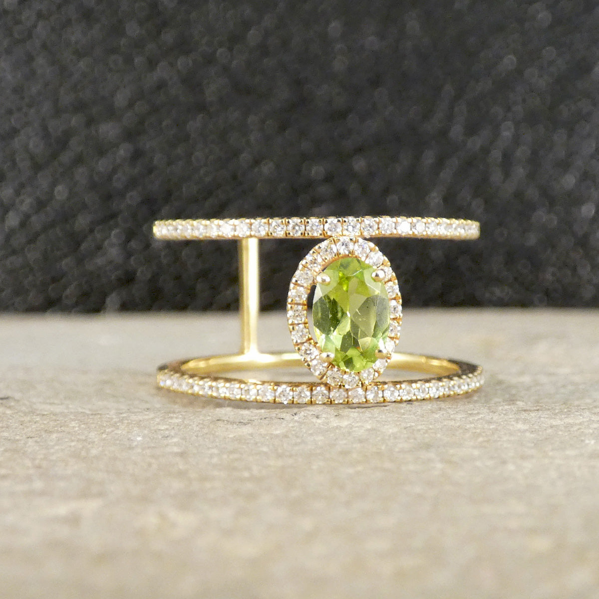Gold ring with a green gemstone on a textured surface