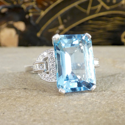 Ring with a large blue topaz gemstone with diamond shoulders on a textured surface