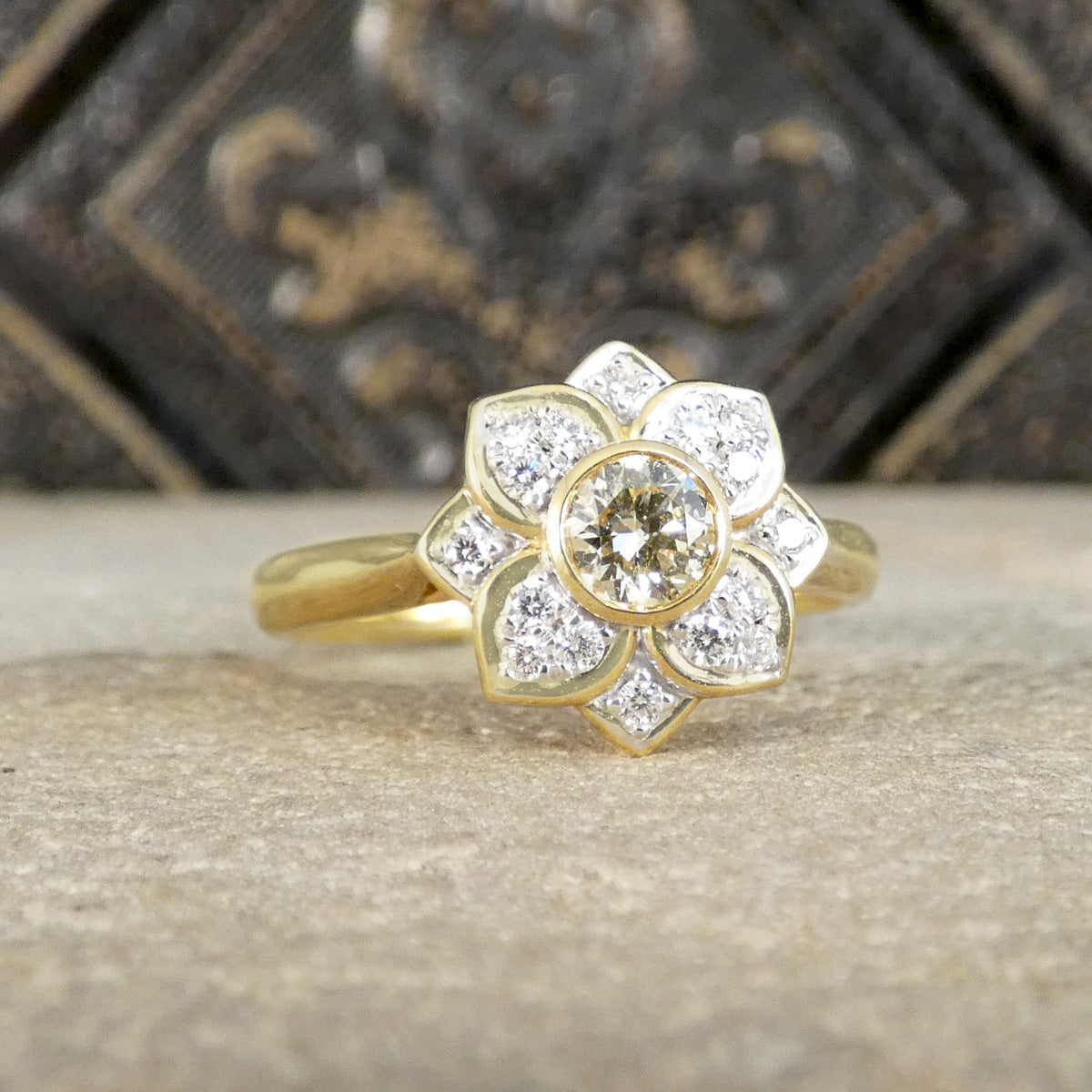 Gold ring with diamond petals on a textured surface