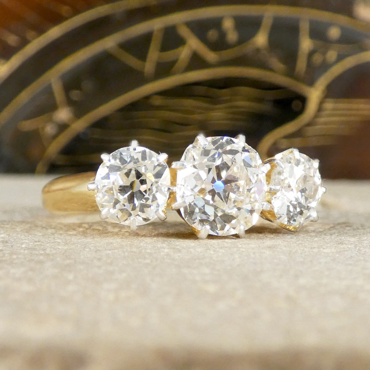 Gold ring with three large diamonds on a textured surface