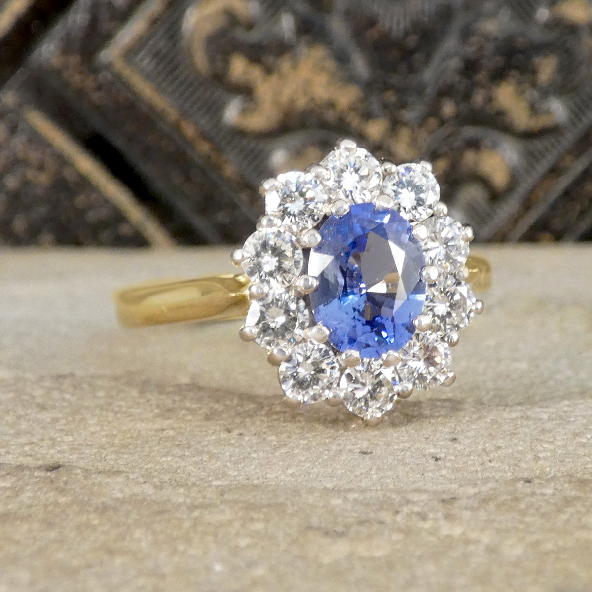 Gold ring with a blue gemstone and diamond accents on a wooden surface.