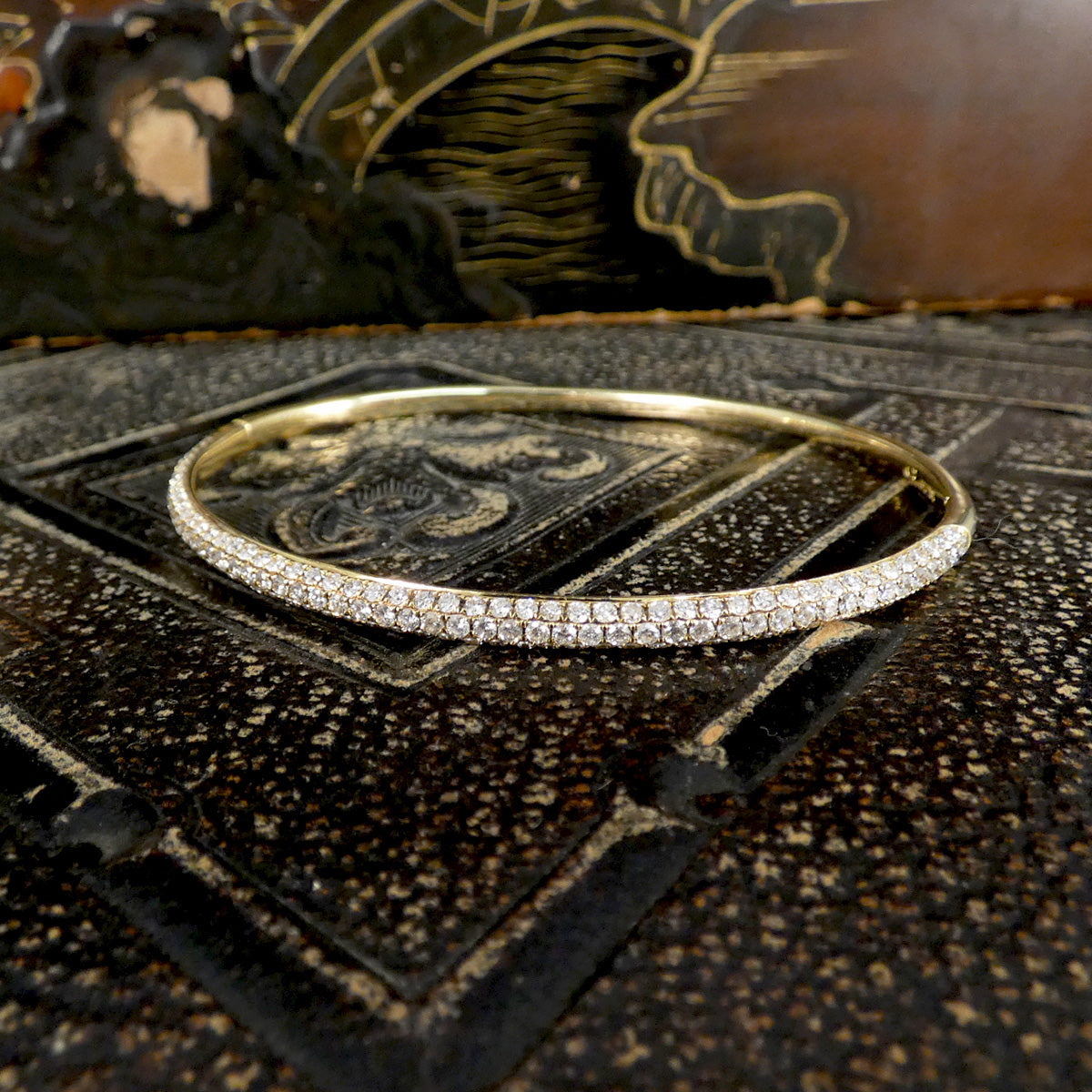 Gold bracelet with diamonds on a textured black surface
