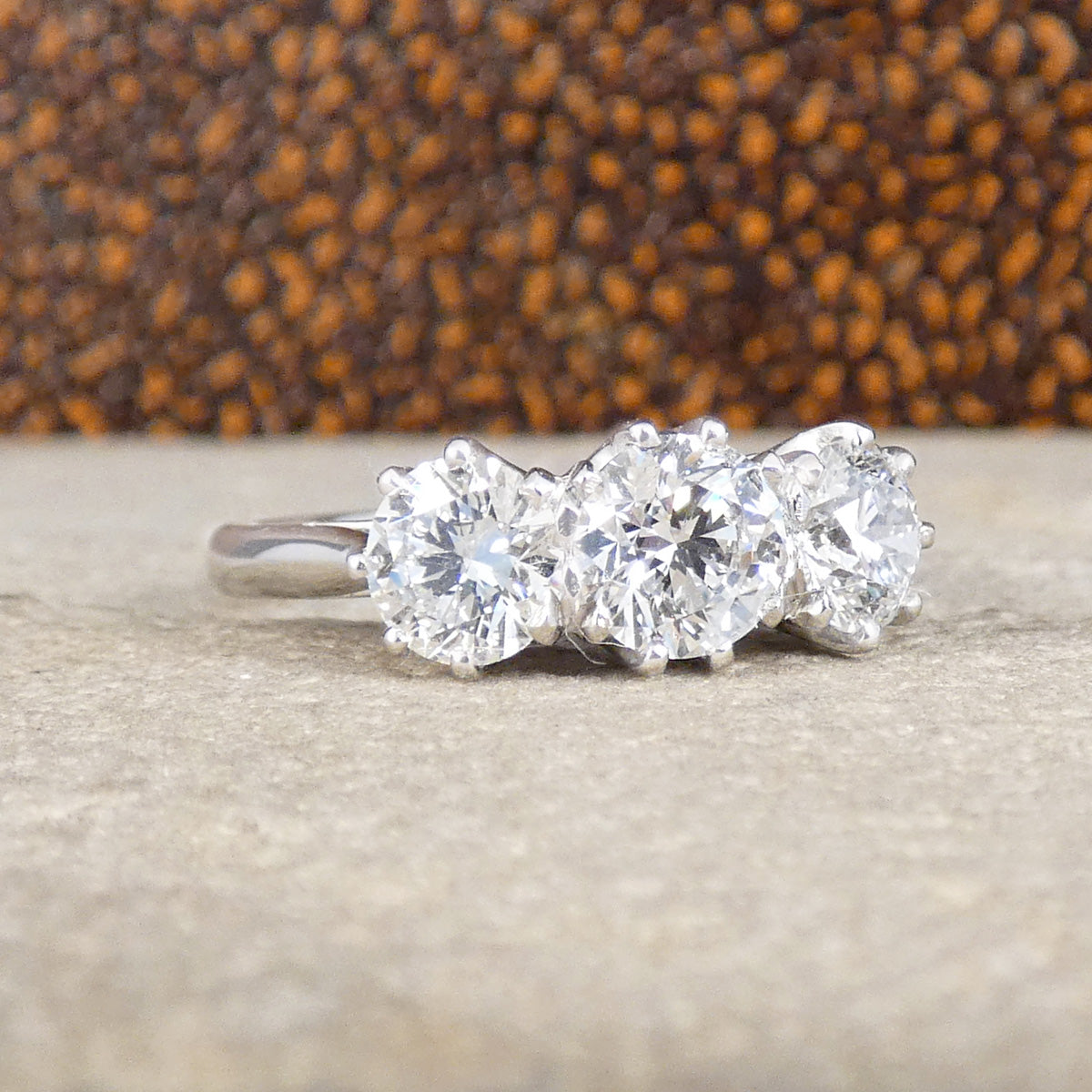 Diamond ring with three stones on a textured surface