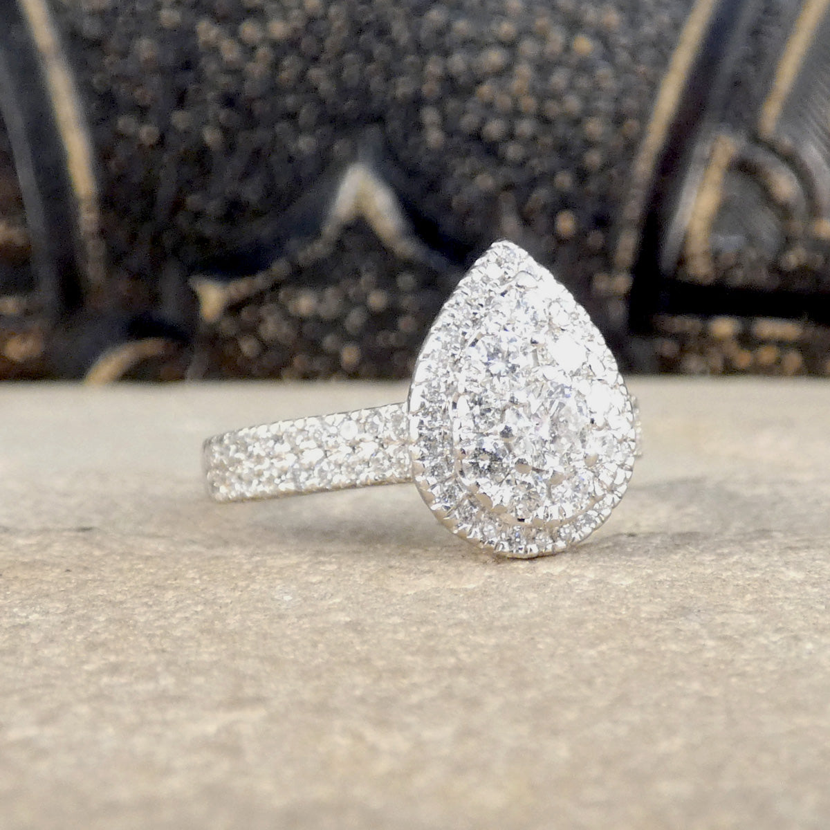 Diamond ring with a teardrop-shaped center on a textured surface