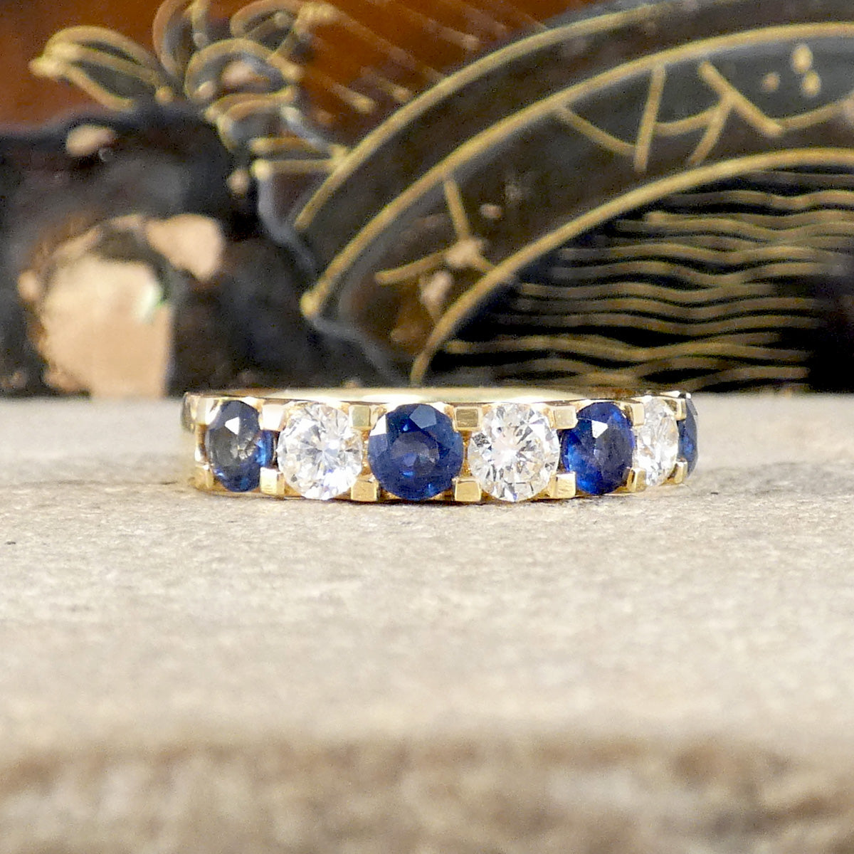 A Sapphire and Diamond half eternity ring in yellow gold.