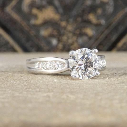 Diamond engagement ring on a textured surface with a blurred decorative background