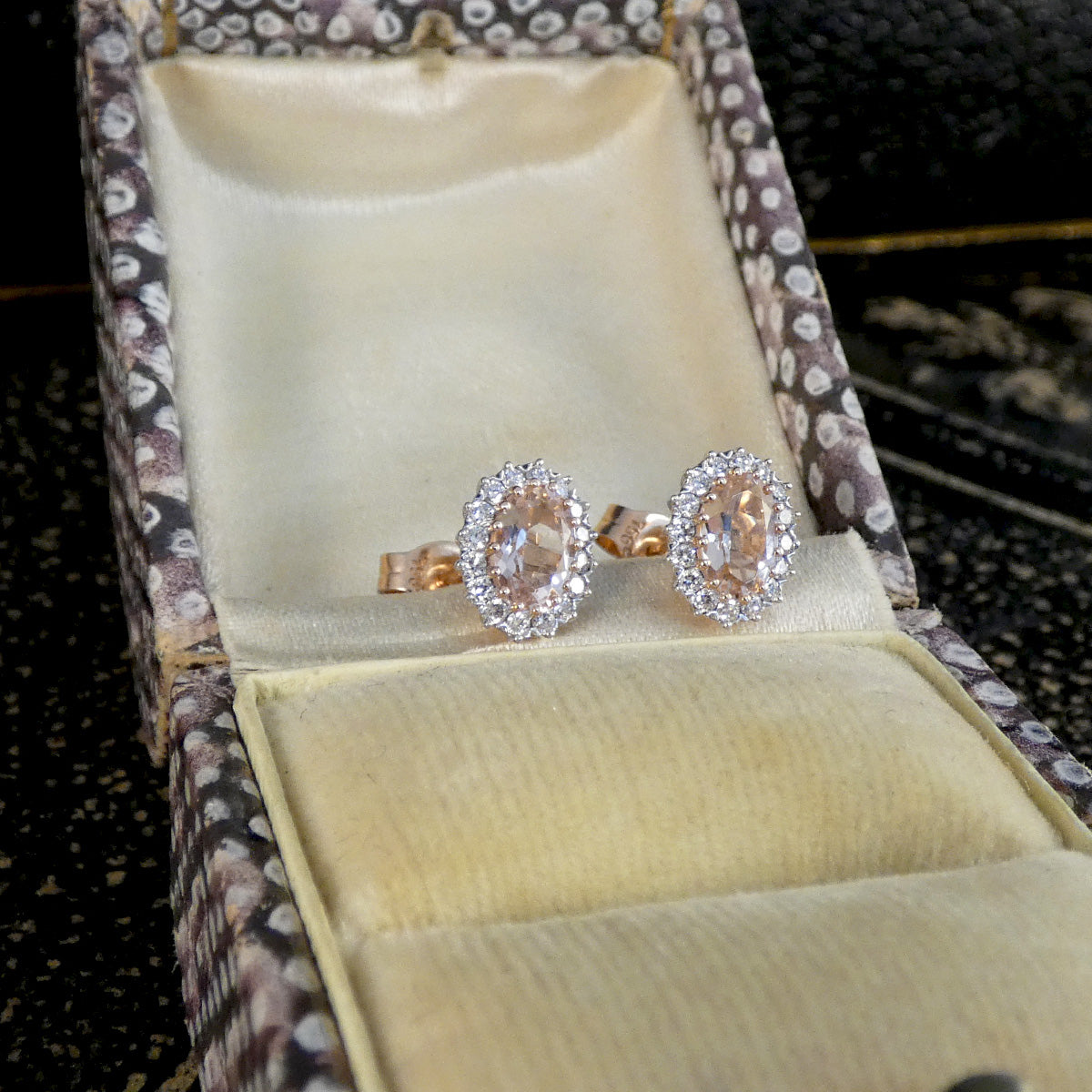 Pair of diamond earrings in a decorative box with a floral pattern.