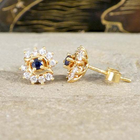Gold earrings with blue gemstones on a beige surface