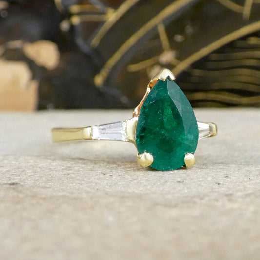 Gold ring with a green emerald stone on a textured surface