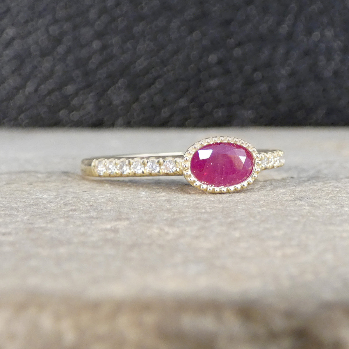 Gold ring with a pink gemstone on a textured surface