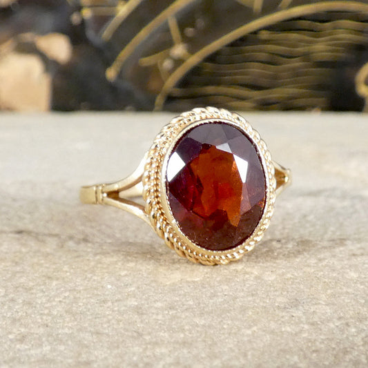 Gold ring with a red garnet gemstone on a textured surface