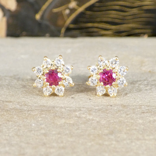 Pair of gold earrings with ruby gemstones on a neutral background