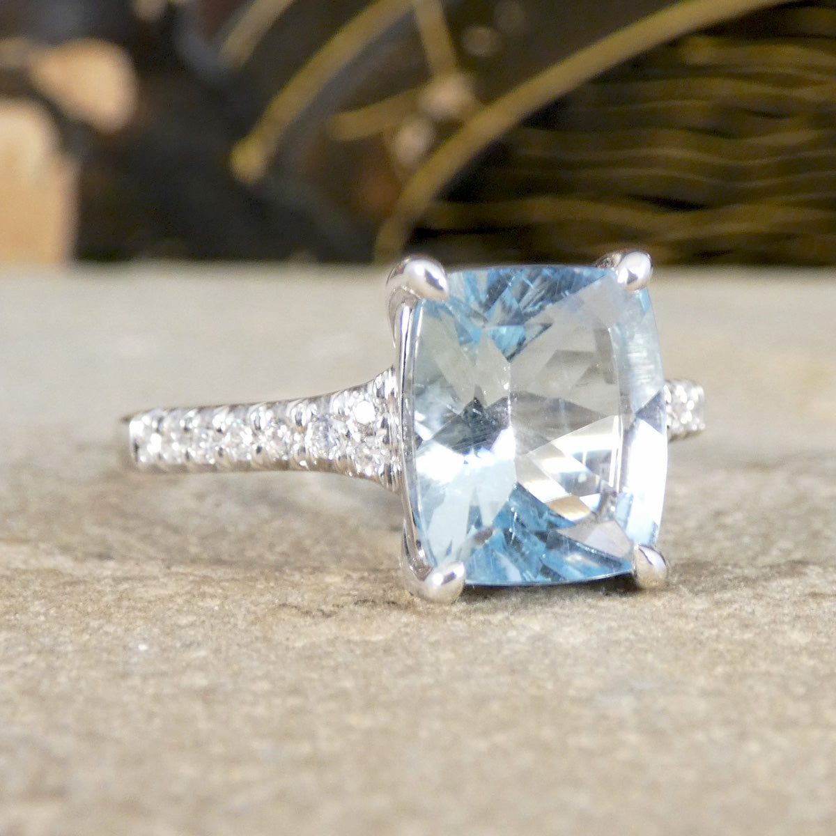 Ring with a large blue gemstone and smaller diamonds on a neutral background