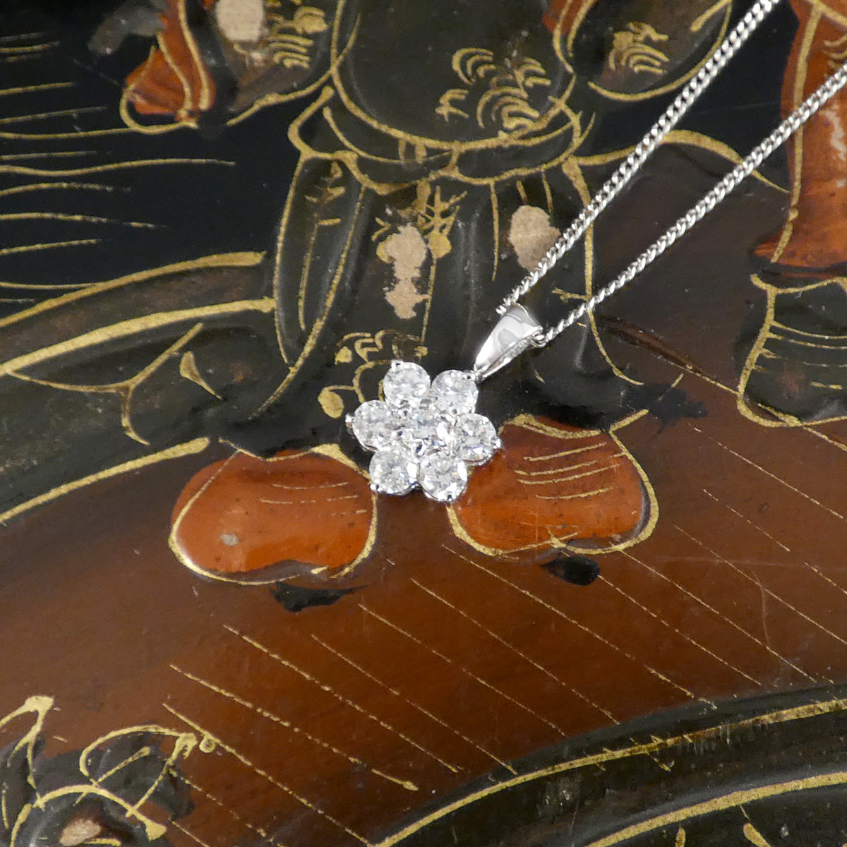white gold necklace with a diamond pendant on an ornate wooden surface