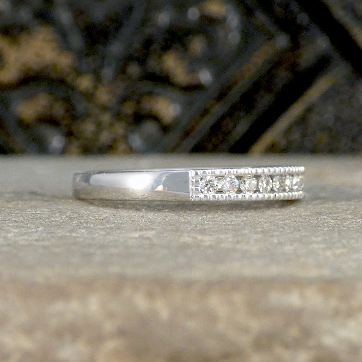 Silver ring with small diamonds on a stone surface