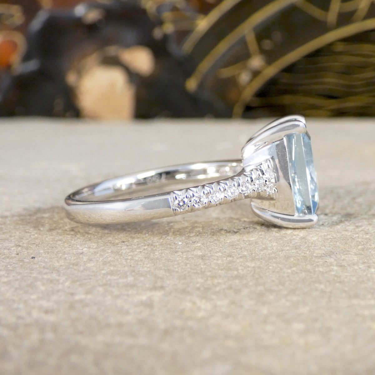 Silver ring with a large rectangular gemstone on a textured surface