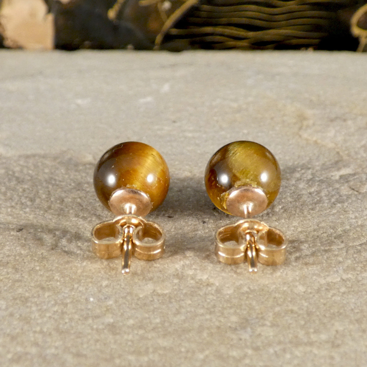 the back of a pair of tigers eye stud earrings on a 9ct yellow gold post