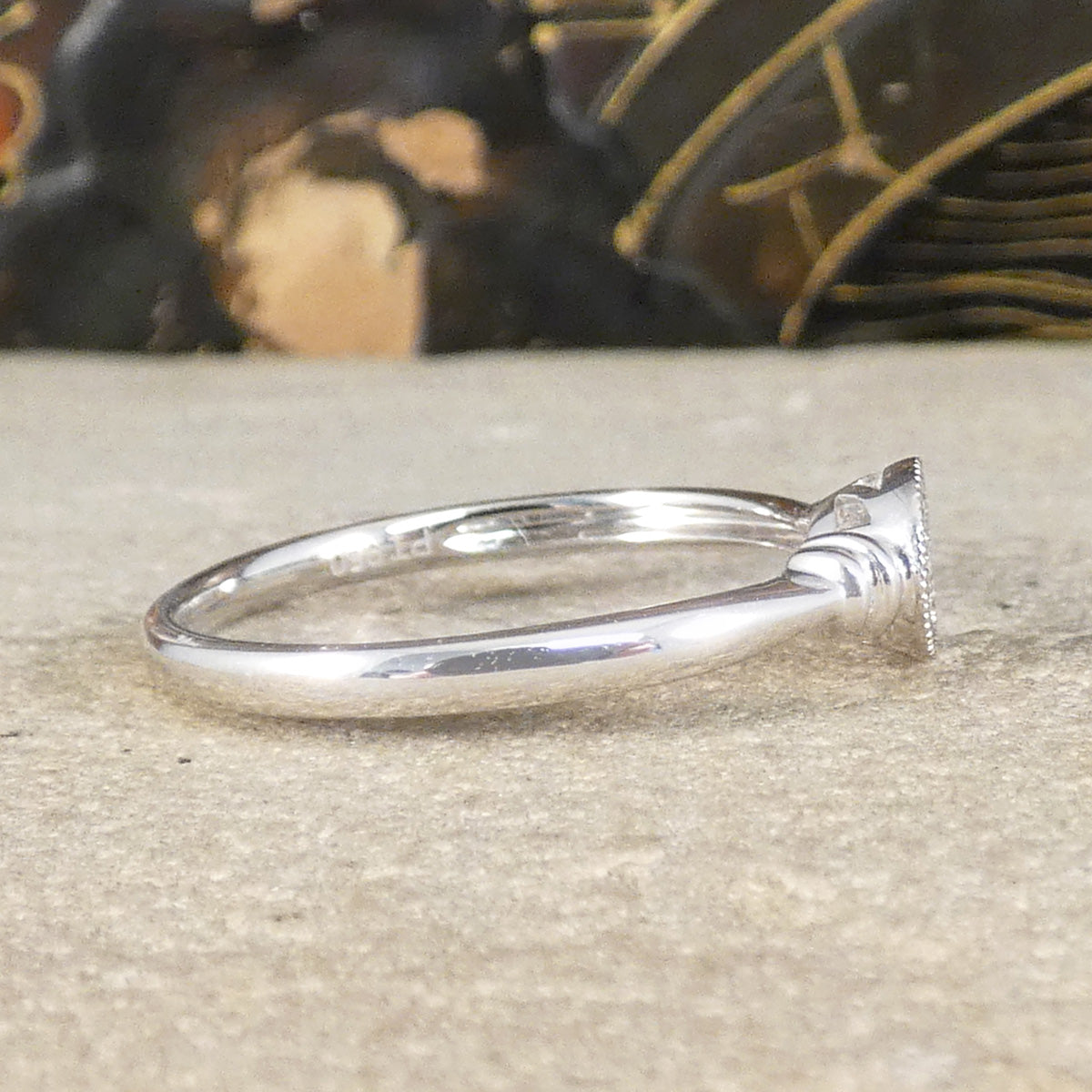 Side view of Diamond set simple and dainty platinum ring with plain polished band.
