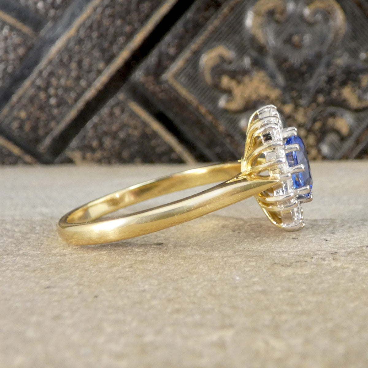 Gold ring with a blue sapphire 
gemstone on a textured surface