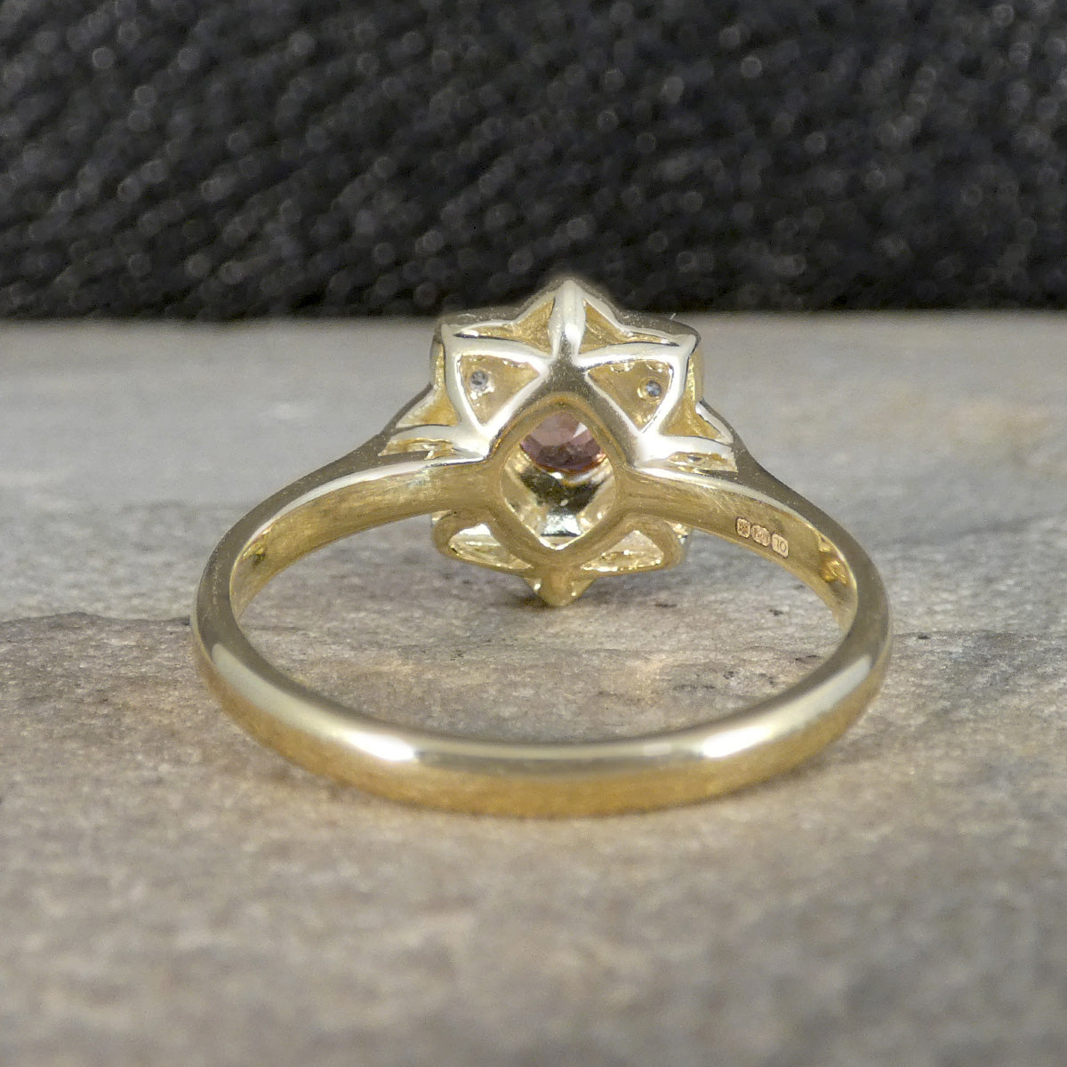 Gold ring with a star-shaped design and central gemstone on a textured surface