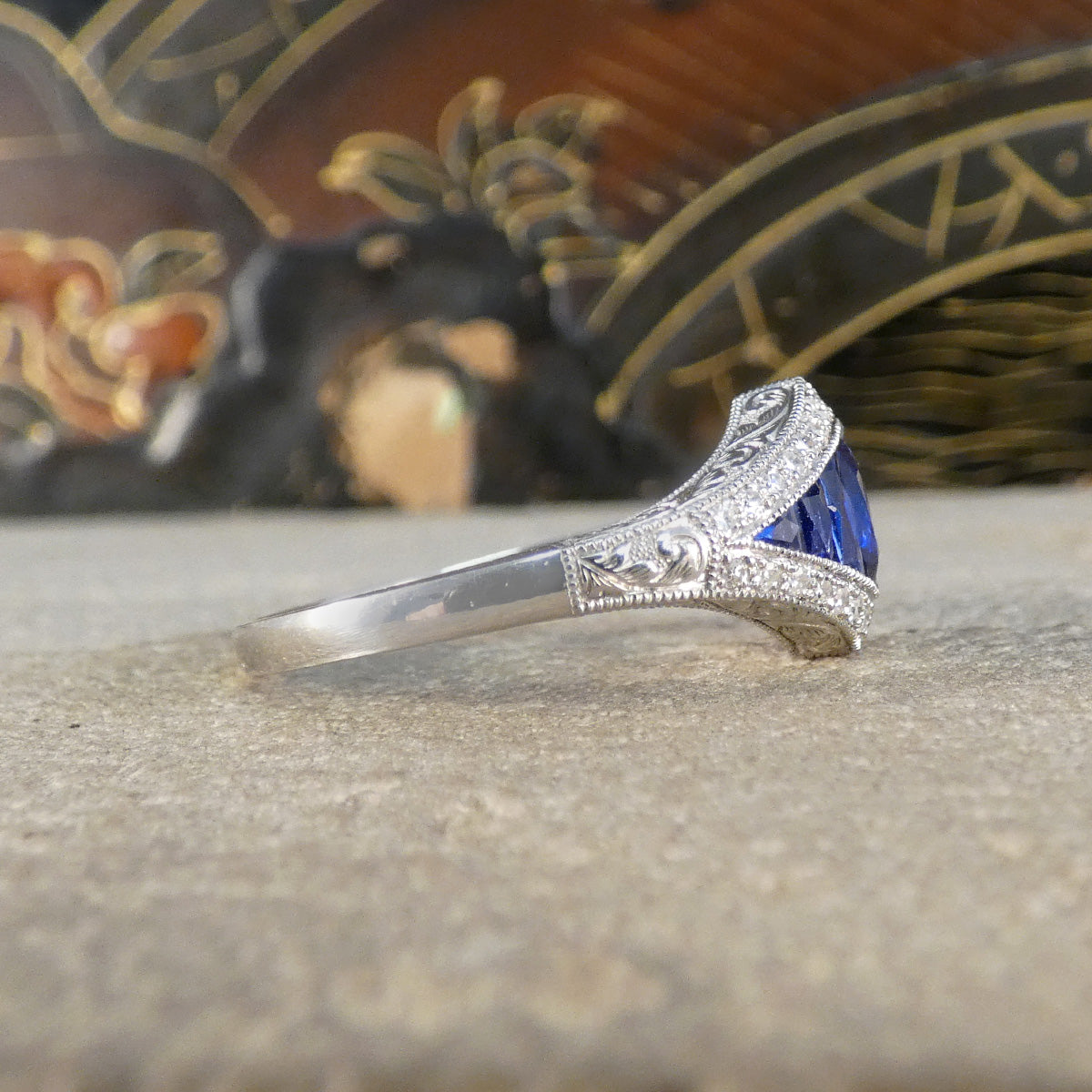 Side view of A gorgeous Art Deco style Sapphire and Diamond cluster ring in Platinum. Showing detail on the shoulder leading to a plain polished band.