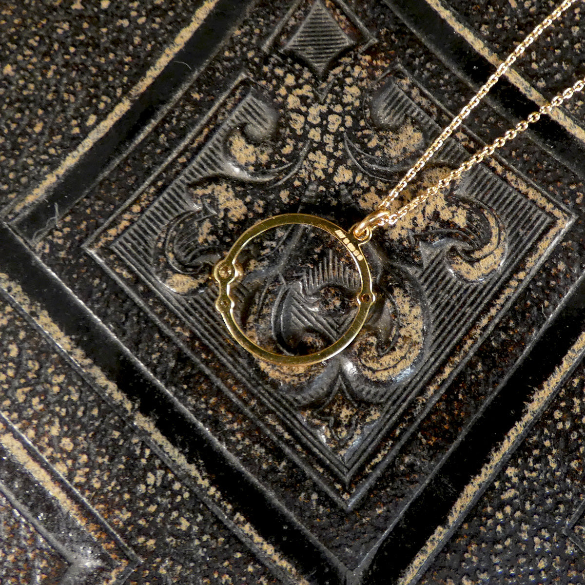 Gold necklace with a pendant on a textured black surface