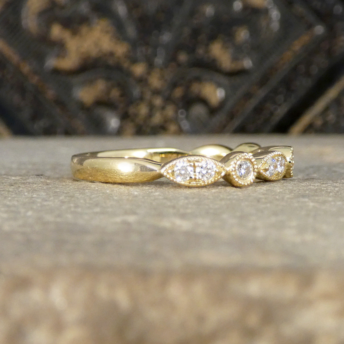 Gold ring with diamond accents on a textured surface
