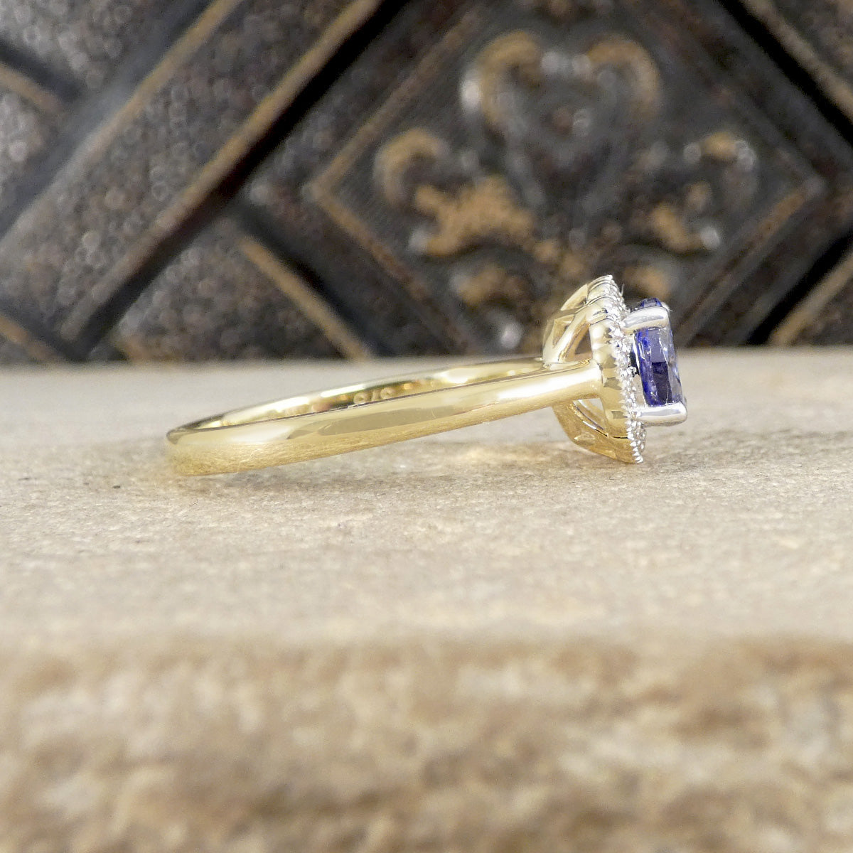 Gold ring with a purple gemstone on a textured surface