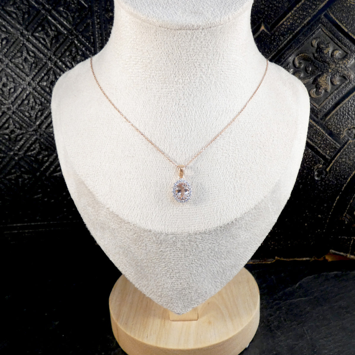Necklace with a pendant on a mannequin bust against a textured black background