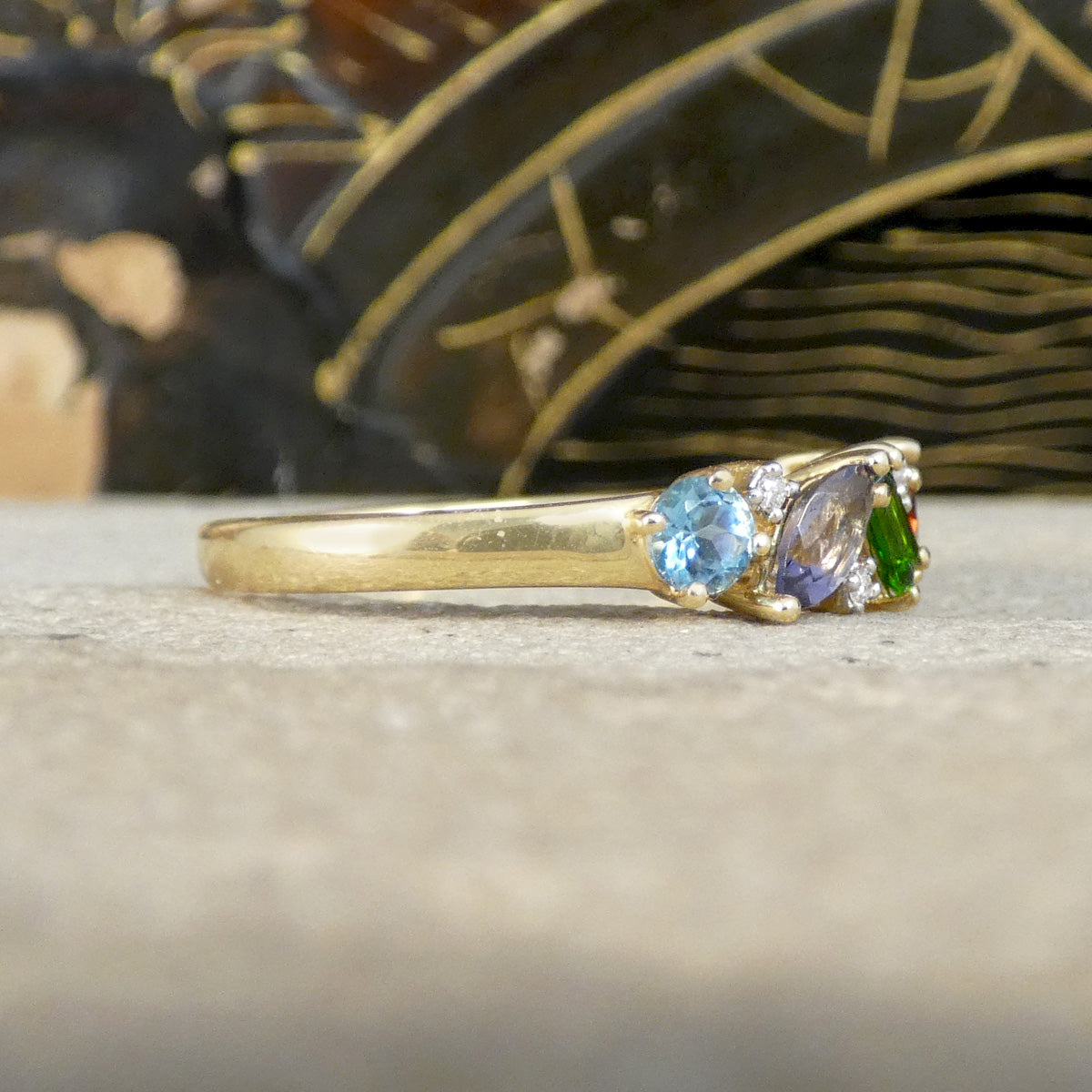 Gold ring with gemstones on a textured surface