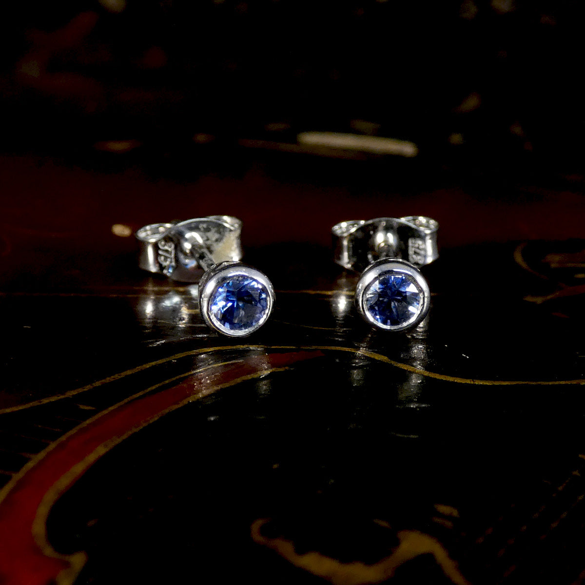 Silver stud earrings with blue gemstones on a dark background