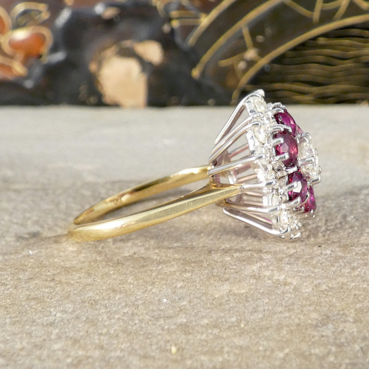 A side view of a ruby and diamond cluster ring in yellow gold
