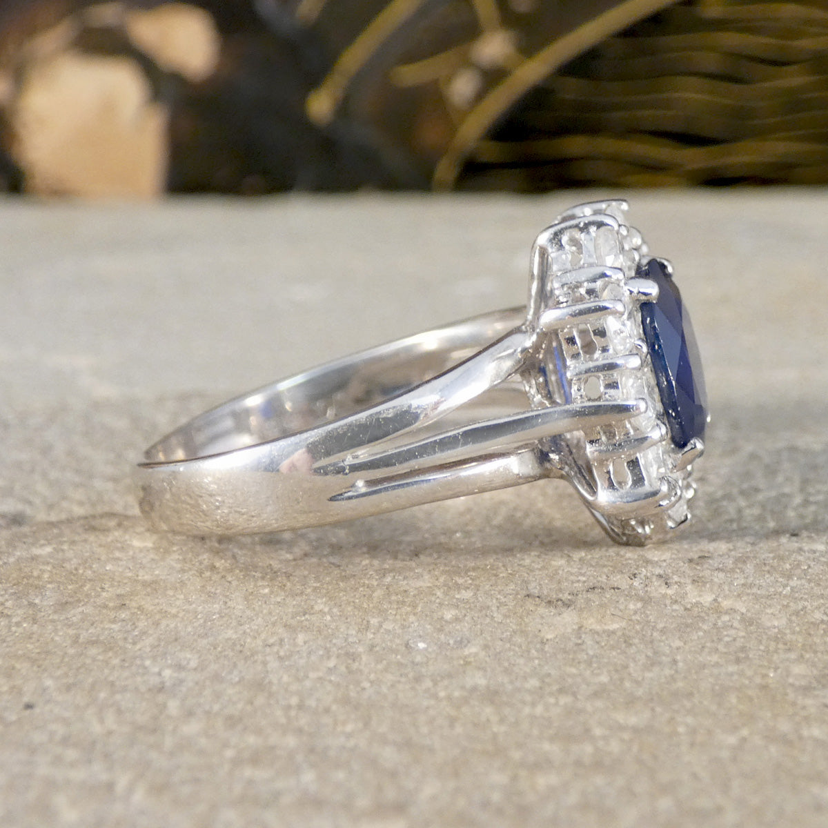 Silver ring with a blue gemstone and diamonds on a textured surface