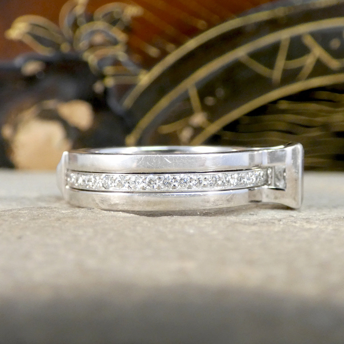 Silver ring with embedded diamonds on a textured surface